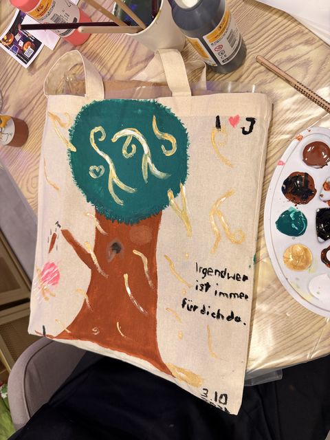 A painted tree and lettering on a tote bag