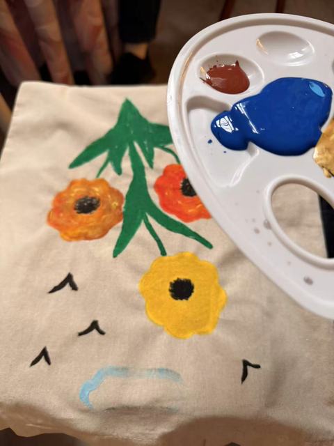 Tote bag painted with orange flowers and green stems
