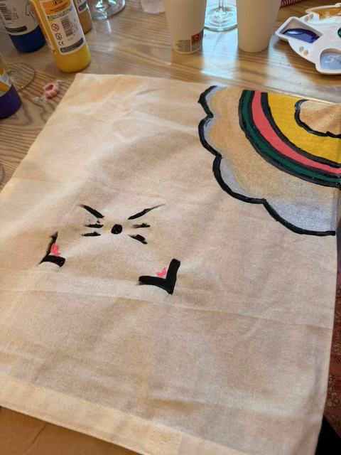 Tote bag painted with a minimalist cat face and a rainbow