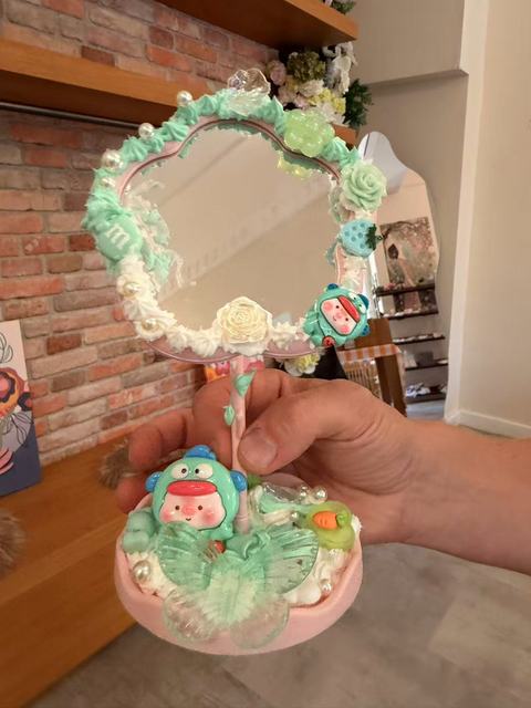 Mirror framed with mint decoden cream and a small figure