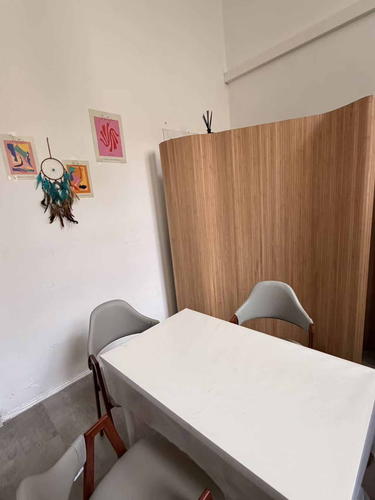 Quiet corner of the studio with a wooden screen, art prints and a dreamcatcher